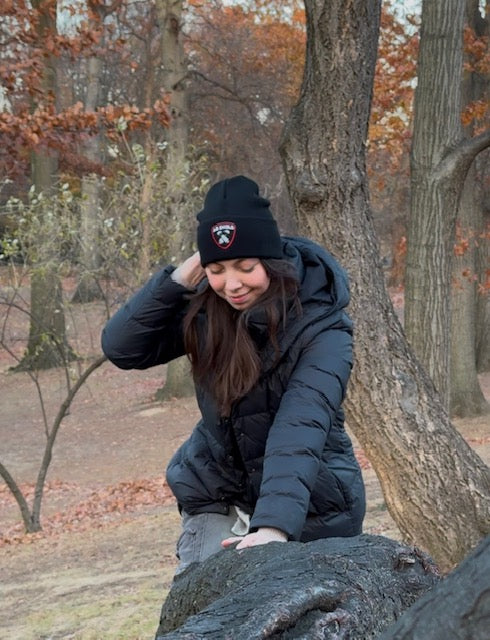 Cute girl climbing tree in Central Park New York City with black Ab Shield beanie and winter jacket.