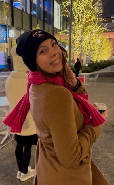 Cute girl in Ab Shield Beanie with hot chocolate. Winter time in New York city with Christmas lights.